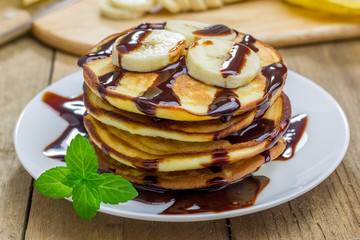 Stack of pancakes with banana and chocolate syrup, closeup