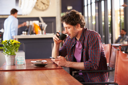 Man at coffee shop, using phone