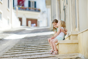 Two adorable little sisters laughing and hugging