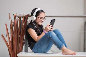 Cute happy girl with glasses listening to music on headphones
