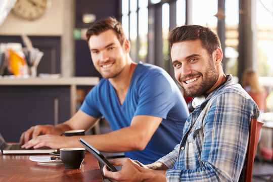 Two young men working on computers at a coffee shop