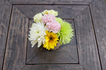 a small bouquet of colorful flowers on a well used old desk or w