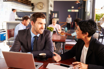 Two business people with laptop meeting in a coffee shop