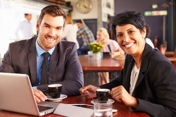 Two business people with laptop meeting in a coffee shop