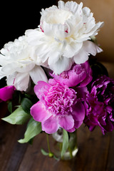 white and pink peonies bouquet from flowers market on a dark wood table in rustic style