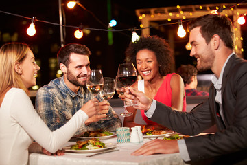 Four friends eating dinner at rooftop restaurant