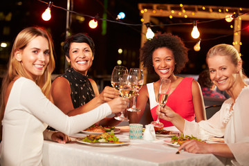 Group of female friends eating dinner at rooftop restaurant