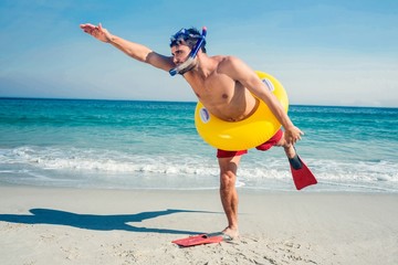 Man wearing flippers and rubber ring at the beach