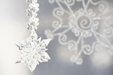 Silver and glass glittery snowflake Christmas ornaments on silver background. 