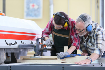 Young trainee in carpentry using sawing machine