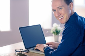Happy businessman with his laptop smiling at camera 