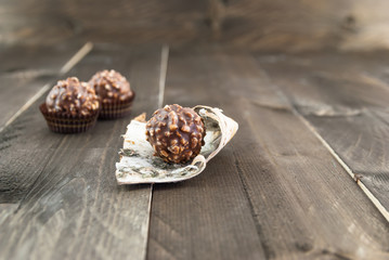 Chocolate bonbons with peanut pieces on color wooden background