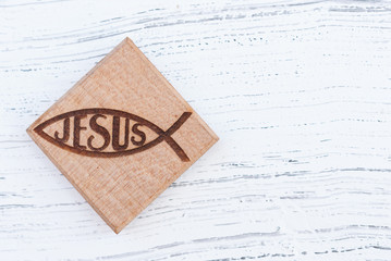 Christian fish symbol carved in wood hanging on old rustic wood background