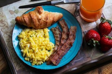American breakfast with scrambled eggs, bacon,croissant,orange juice and fruits, overhead view