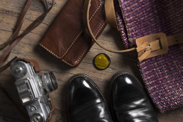 Black shoes, film camera and wallet on the wooden table