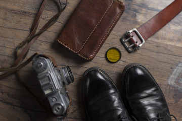 Black shoes, film camera and wallet on the wooden table