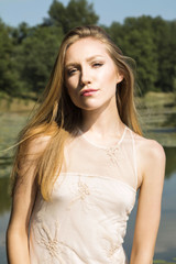 Fototapeta na wymiar Girl in white dress outdoor, posing on lake shore 