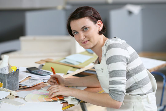 Young woman painter sitting at working table