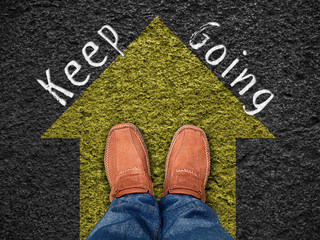 Inspiration quote : " Keep going" on aerial view of shoe on road