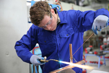 student in plumbing professional training, working on copper