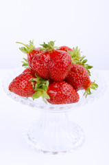 Transparent glass bowl with strawberries on white background
