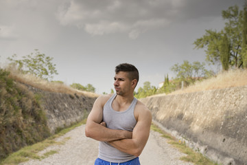 Casual sportsman runner posing in road with cloudy day light