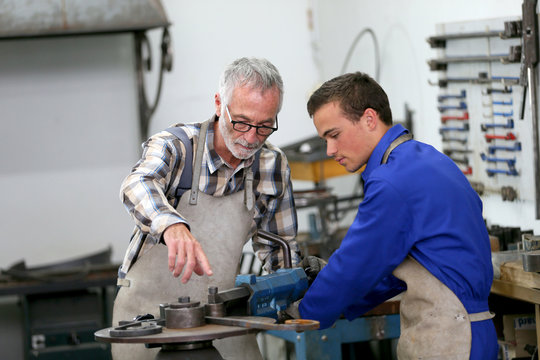 Young man in ironworks training with professional teacher