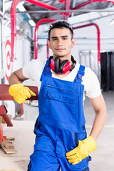 Asian carpenter with electric saw in workshop