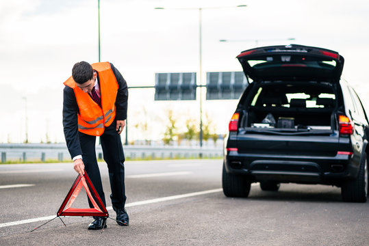 Mann mit Autopanne stellt Warndreieck auf