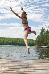 tween girl jumping off a dock into a lake
