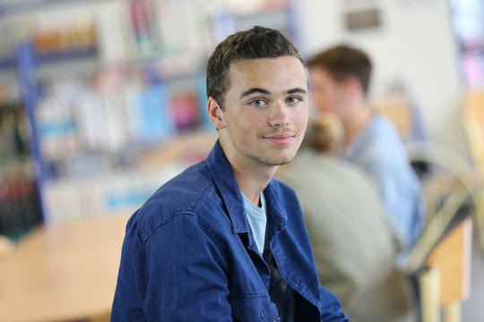 Student boy sitting on table in library room