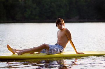 teen boy sitting on a surfboard