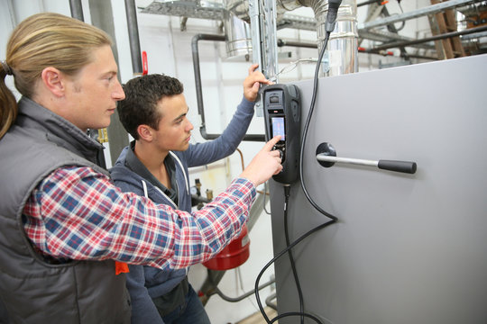 Young man in professional training measuring heat pump temperature