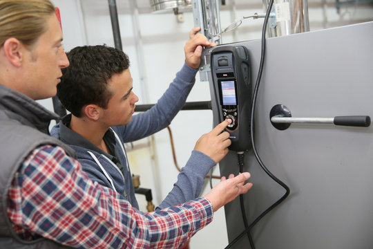 Young man in professional training measuring heat pump temperature