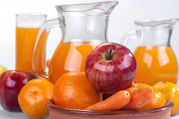 apple, orange and carrots with fresh juice in the background