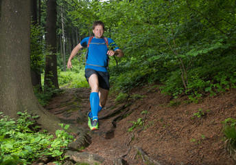 man running on the trail down the hill in the forest