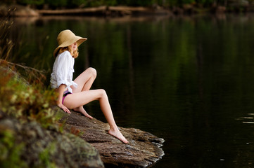 girl sitting on a rock by a lake