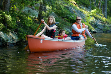 family paddling a canoe on a wilderness lake