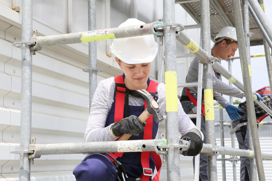 Young woman in professional training working on scaffolding