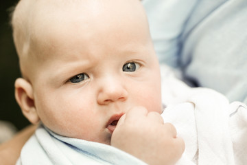 Portrait of a unique blue-eyed baby boy in teething pain