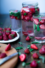 strawberry mint infused water decorated in rustic style on dark wood table background