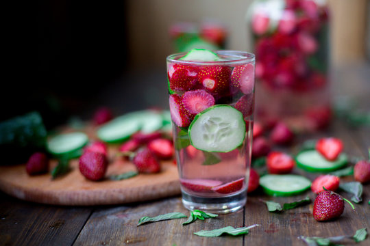 strawberry mint cucumber infused water decorated in rustic style on dark wood table background