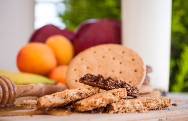 biscuits with honey and honey dipper with milk and fruits