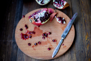 organic pomegranate open cut in half and full one on a wooden dark table background decorated in rustic style