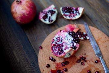 organic pomegranate open cut in half and full one on a wooden dark table background decorated in rustic style