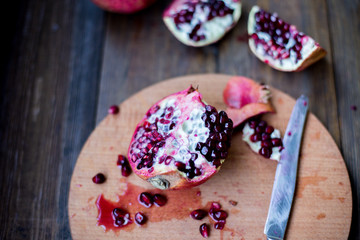 organic pomegranate open cut in half and full one on a wooden dark table background decorated in rustic style