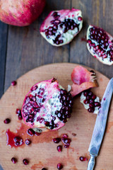 organic pomegranate open cut in half and full one on a wooden dark table background decorated in rustic style