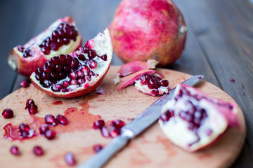 organic pomegranate open cut in half and full one on a wooden dark table background decorated in rustic style