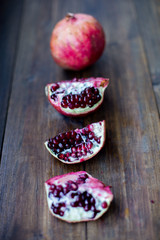 organic pomegranate open cut in half and full one on a wooden dark table background decorated in rustic style