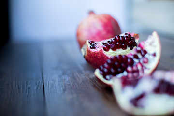 organic pomegranate open cut in half and full one on a wooden dark table background decorated in rustic style